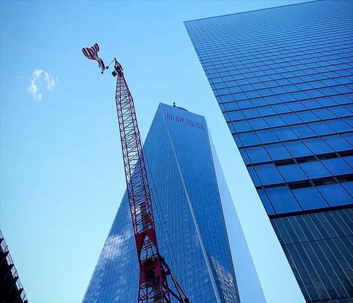 crane with a flag on top and tall buildings behind it